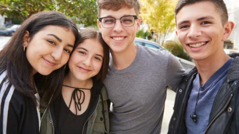 A photo of four students in a group, smiling and looking happy